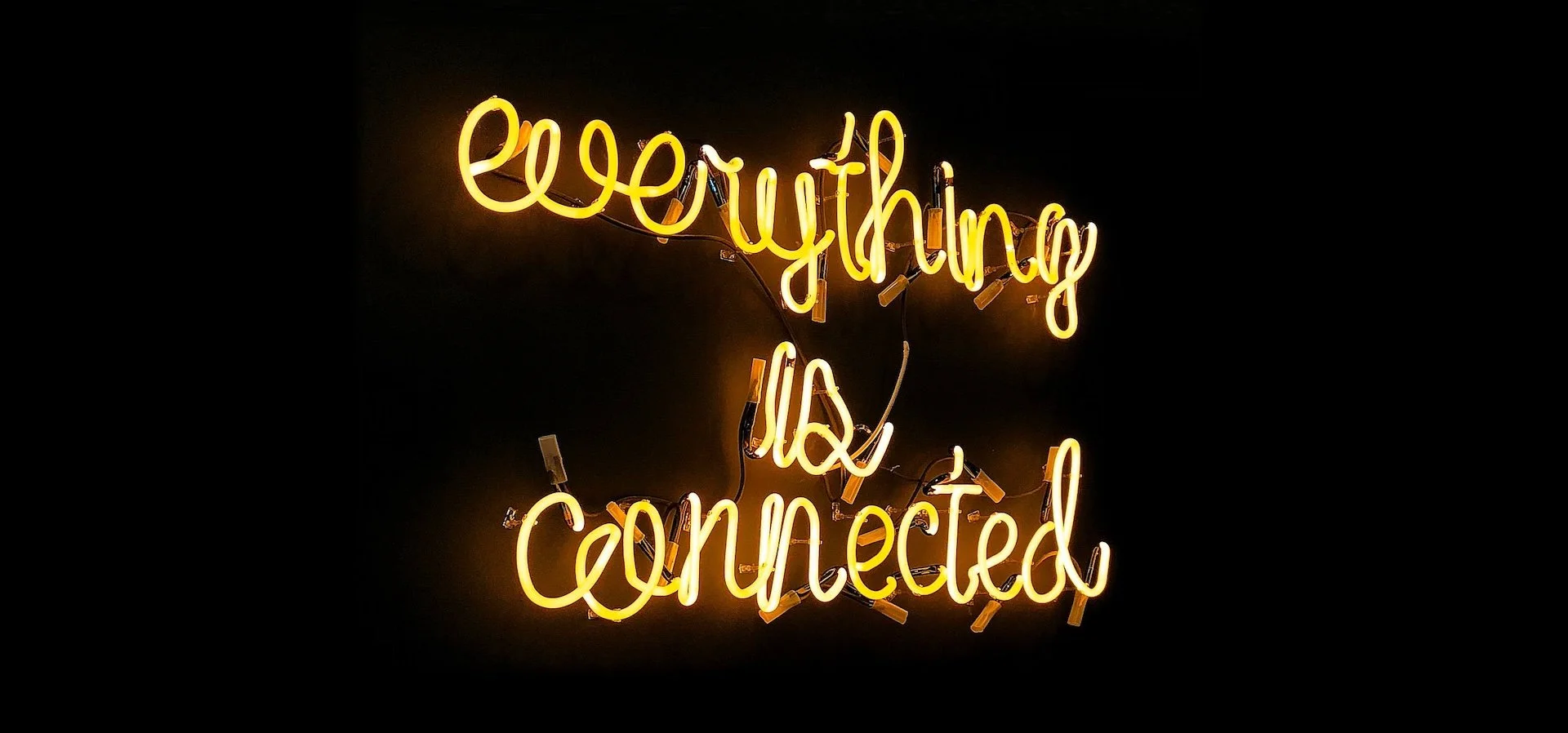 Žuti neonski natpis &bdquo;everything is connected&rdquo; svetli na crnoj pozadini.