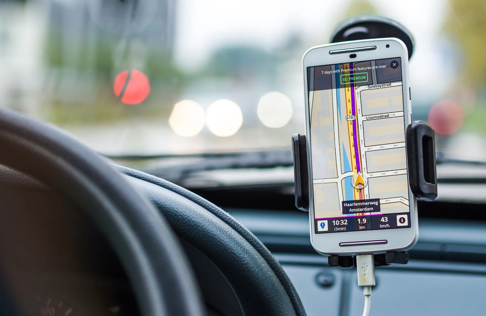 Pametni telefon sa uključenom GPS navigacijom pričvr&scaron;ćen je za &scaron;ofer&scaron;ajbnu automobila pored volana.