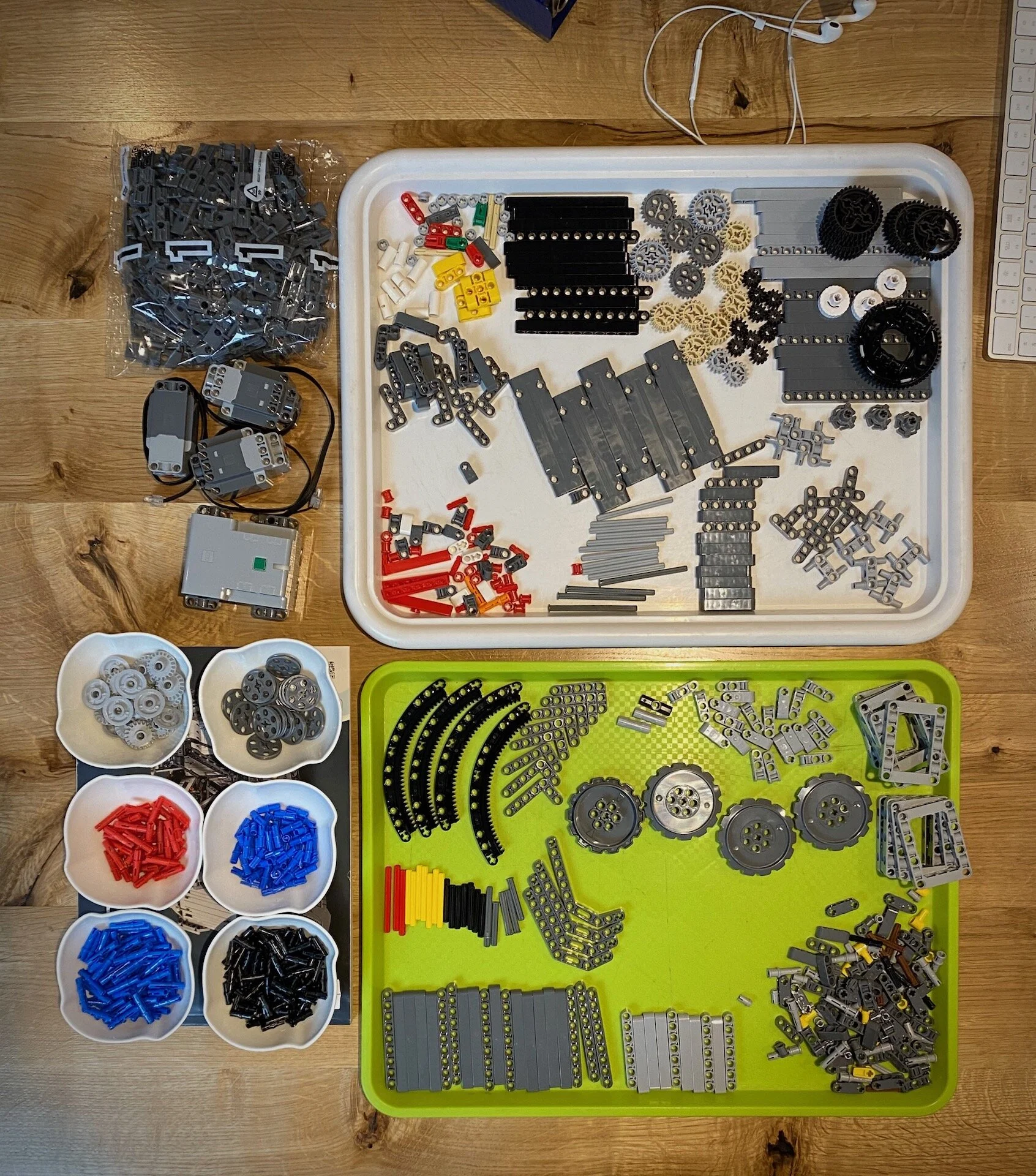 Brojni Lego Technic delovi razvrstani su po boji i obliku u posude na drvenom podu.