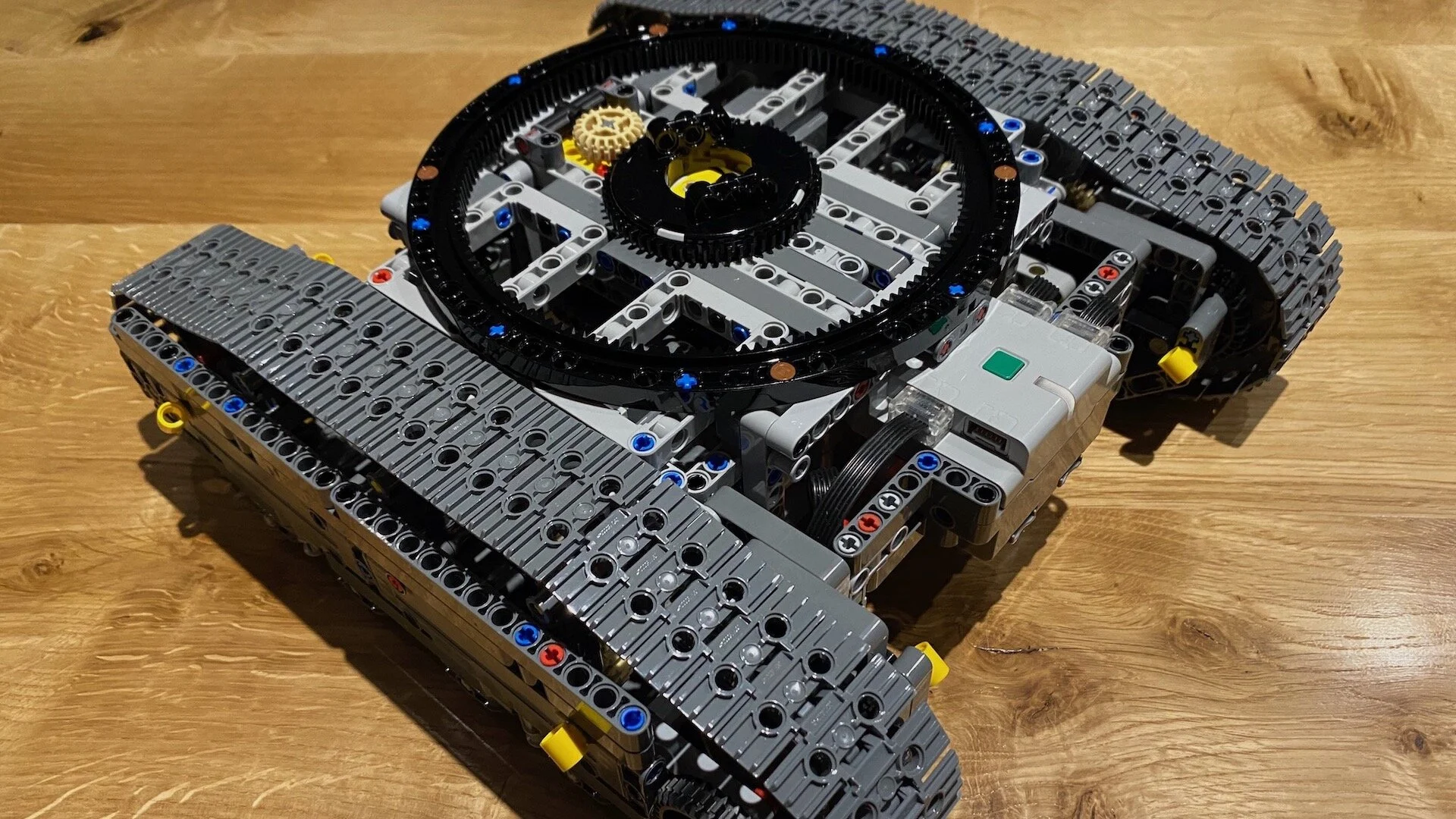 Delimično sastavljena gusenična &scaron;asija Lego Technic bagera na drvenom podu.