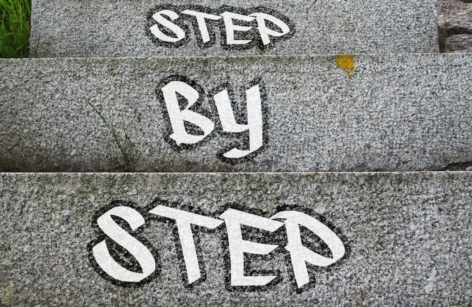 Betonske stepenice sa belim slovima &bdquo;STEP BY STEP&rdquo;.